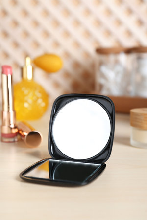 Stylish pocket mirror and cosmetic products on beige tableの写真素材