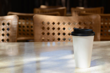 Takeaway coffee cup on beige table in cafe, space for text