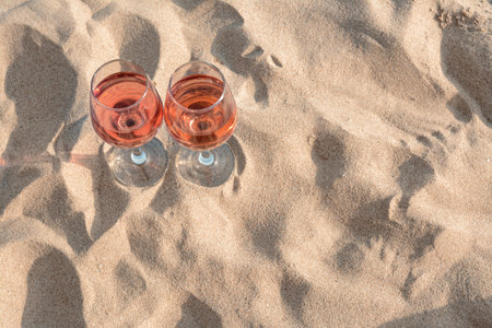 Glasses of tasty rose wine on sand, above view. Space for textの写真素材