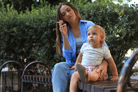 Mother with cigarette and child outdoors. Don't smoke near kidsの写真素材