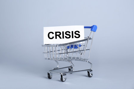 Mini metal cart and word Crisis on light backgroundの写真素材