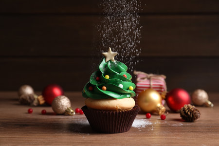 Sprinkling powdered sugar on Christmas tree shaped cupcakeの写真素材