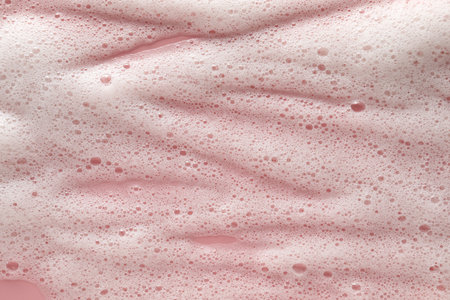 White washing foam on pale pink background, top view