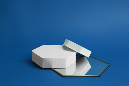 Product photography props. Hexagonal shaped podiums and mirror on blue background