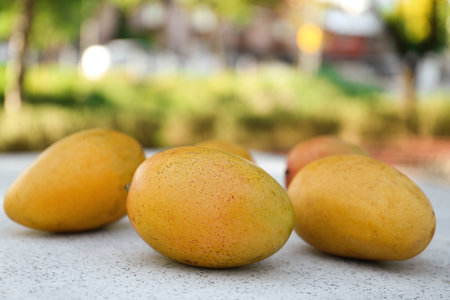 Delicious ripe juicy mangos on table outdoorsの写真素材