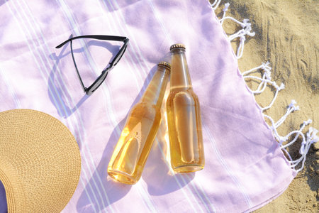 Bottles of beer and beach accessories on sand, flat layの写真素材