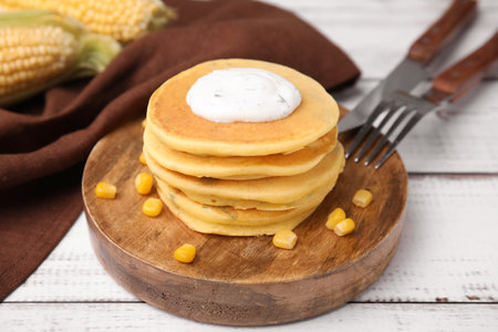 Tasty corn pancakes with sweet kernels and sauce served on white wooden table, closeupの写真素材