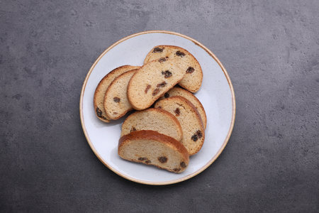 Plate of sweet hard chuck crackers with raisins on gray table, top view