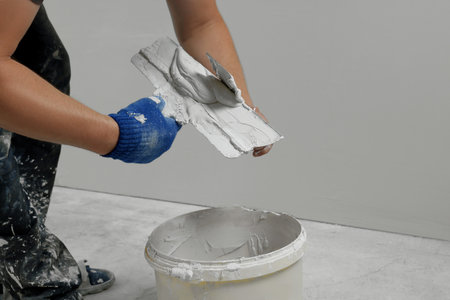Professional worker putting plaster on putty knife indoors, closeupの写真素材