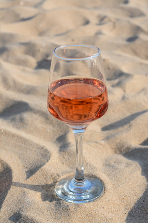 Glass of tasty rose wine on sandの写真素材