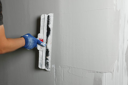 Professional worker plastering wall with putty knife, closeupの写真素材