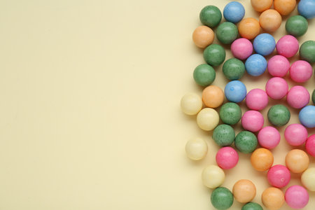 Many bright chewy gumballs on beige background, flat lay. Space for textの写真素材