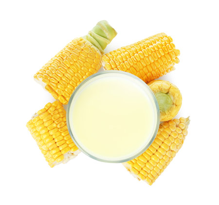 Tasty fresh corn milk in glass and cobs on white background, top viewの写真素材