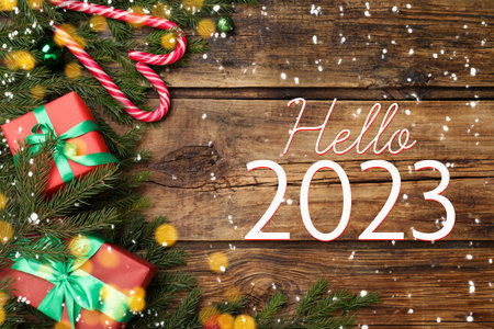 Hello 2023. Flat lay composition with fir tree branches and festive decor on wooden background