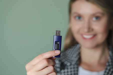 Woman holding usb flash drive against green background, focus on handの写真素材