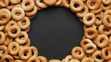 Frame made of tasty dry bagels (sushki) on black background, flat lay. Space for text