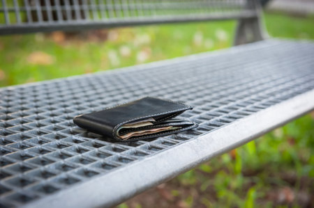 Black wallet on metal bench outdoors. lost and foundの写真素材