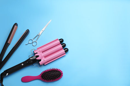 Flat lay composition of professional hairdresser tools on light blue background, space for textの写真素材