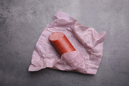 Fresh tasty sausage in beeswax food wrap on gray table, top view