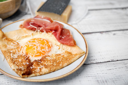 Delicious crepe with egg on white wooden table, closeup. Breton galetteの写真素材