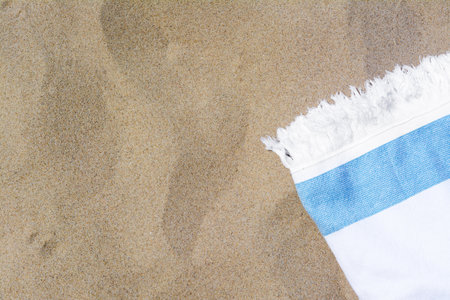 White and light blue striped towel on sandy beach, top view. Space for textの写真素材