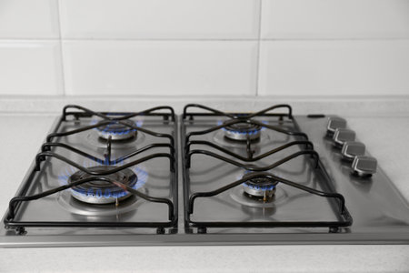 Gas cooktop with burning blue flames in kitchen