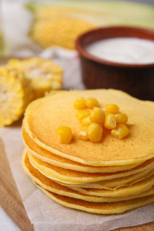 Stack of tasty corn pancakes with sweet kernels served on table, closeup