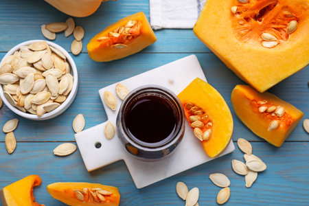 Flat lay composition with fresh pumpkin seed oil in glass jar on blue wooden tableの写真素材