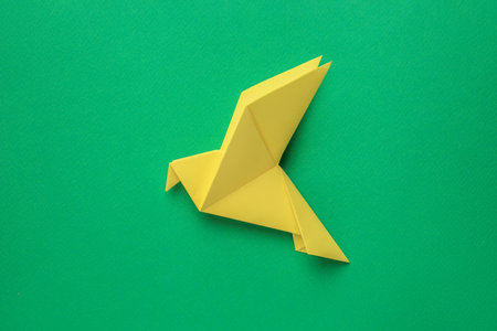 Beautiful yellow origami bird on green background, top viewの写真素材