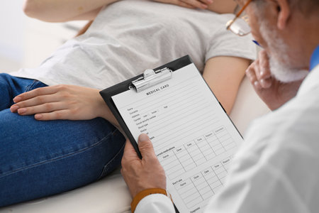 Doctor filling patient's medical card in clinic, closeupの写真素材