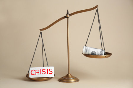 Scale with word Crisis and money on beige background