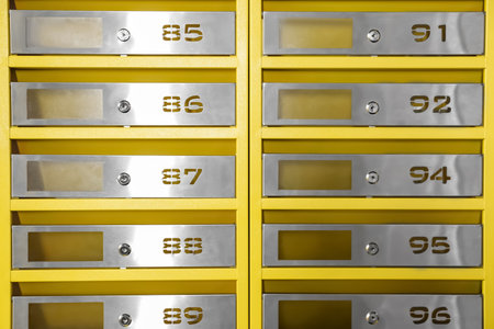 Many closed metal mailboxes with keyholes and numbers as backgroundの写真素材