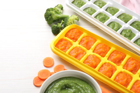 Purees in ice cube trays ready for freezing and ingredients on white wooden table. Space for textの写真素材