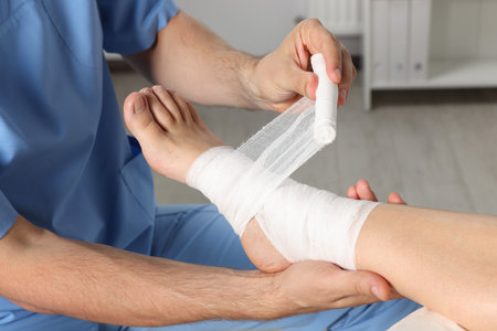 Doctor applying bandage onto patient's foot in hospital, closeupの写真素材