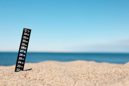 Weather thermometer in sand near sea, space for textの写真素材