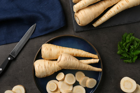 Whole and cut parsnips on black table, flat layの写真素材