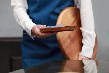 Waitress holding wooden tray with tips and receipt in cafe, closeupの写真素材