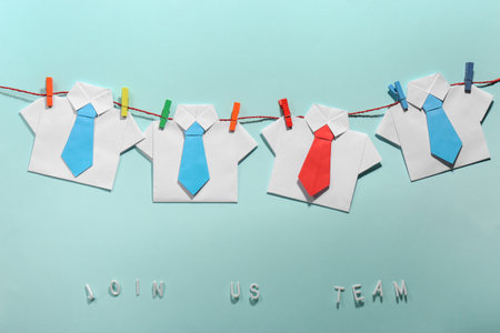 Many paper shirts and phrase Join Us Team on light blue background, flat lay. Recruiter searching employeeの写真素材