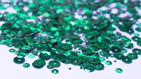 Many beautiful green sequins on white background. close-up