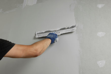 Professional worker plastering wall with putty knife, closeupの写真素材