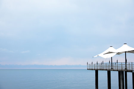 Beautiful view of the pier with beach umbrellas near the sea. Space for text