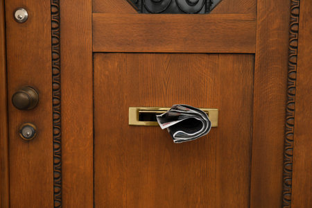 Mail slot with newspaper in beautiful wooden door