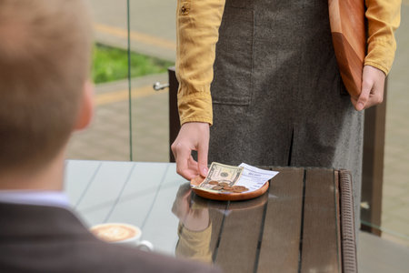 Waitress taking tips from wooden table in outdoor cafe, closeupの写真素材