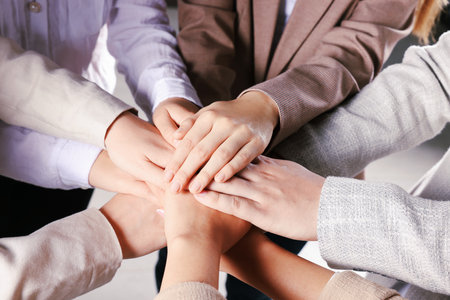 Group of people holding hands together indoors, closeup. unity concept