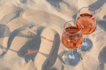 Glasses of tasty rose wine on sand, space for textの写真素材