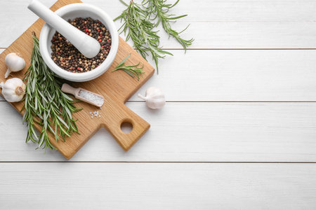 Flat lay composition with fresh green rosemary and mortar on white wooden table. Space for textの写真素材