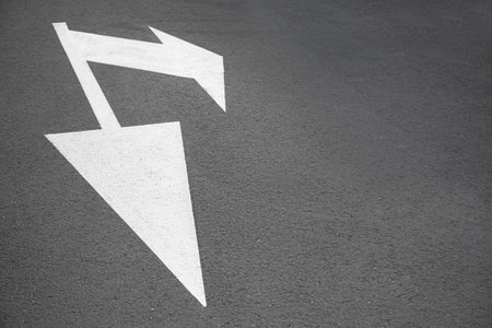 White painted arrow markings on road outdoors, space for textの写真素材