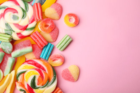 Many different jelly candies and lollipops on pink background, flat lay. Space for textの写真素材