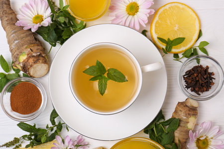 Flat lay composition with cup of delicious tea, honey and ginger on white wooden tableの写真素材