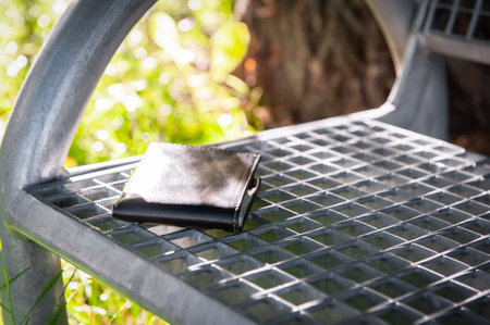 Black wallet on metal bench outdoors. lost and found